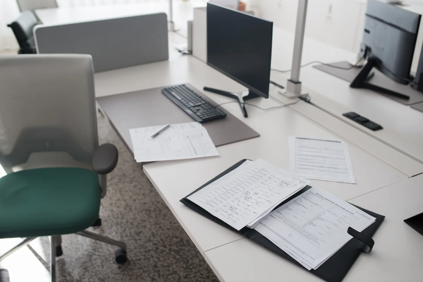 Documentos y una carpeta sobre un escritorio de oficina con monitor